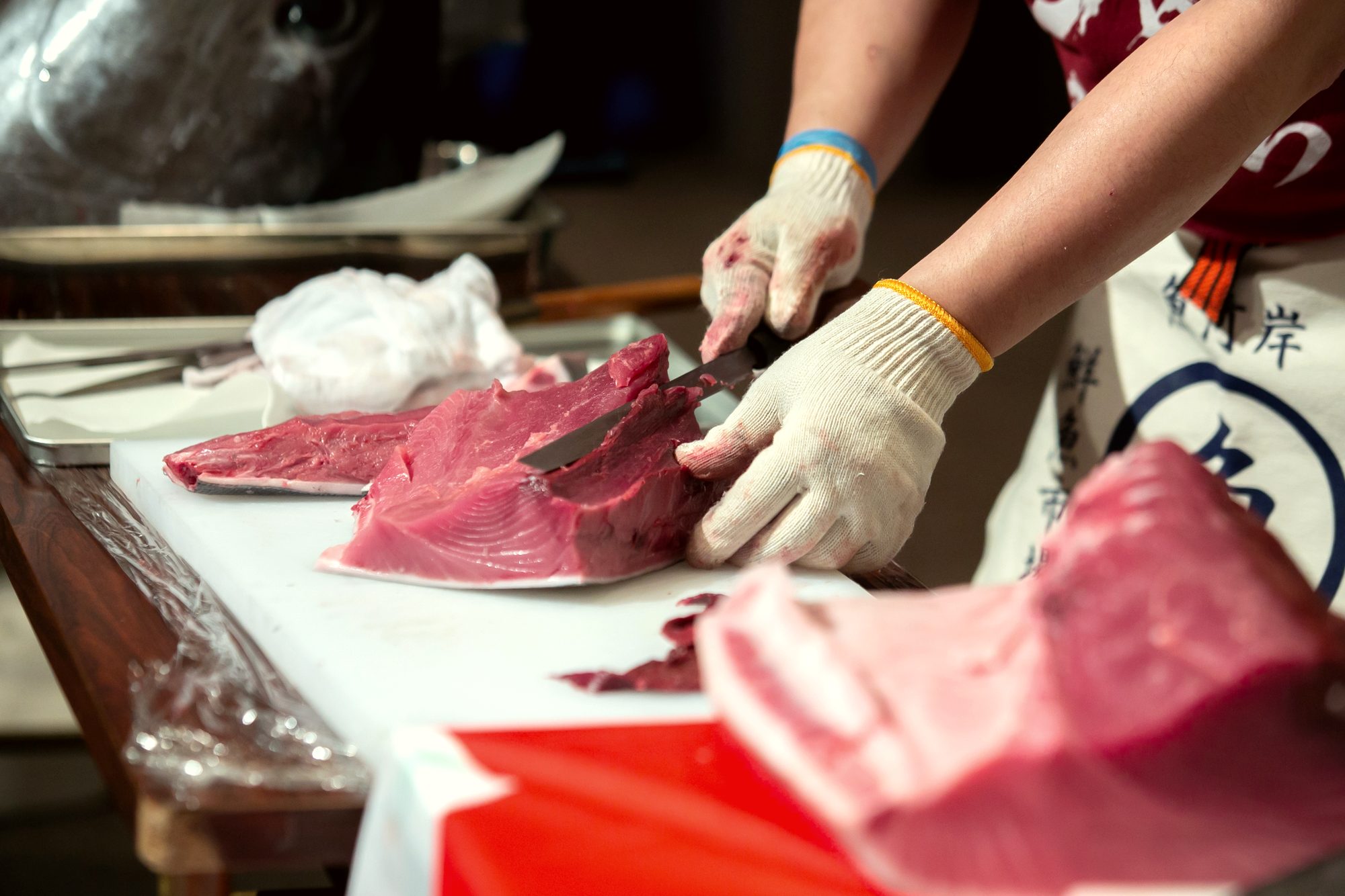 Close-up of the knife portioning a block of deep-red tuna