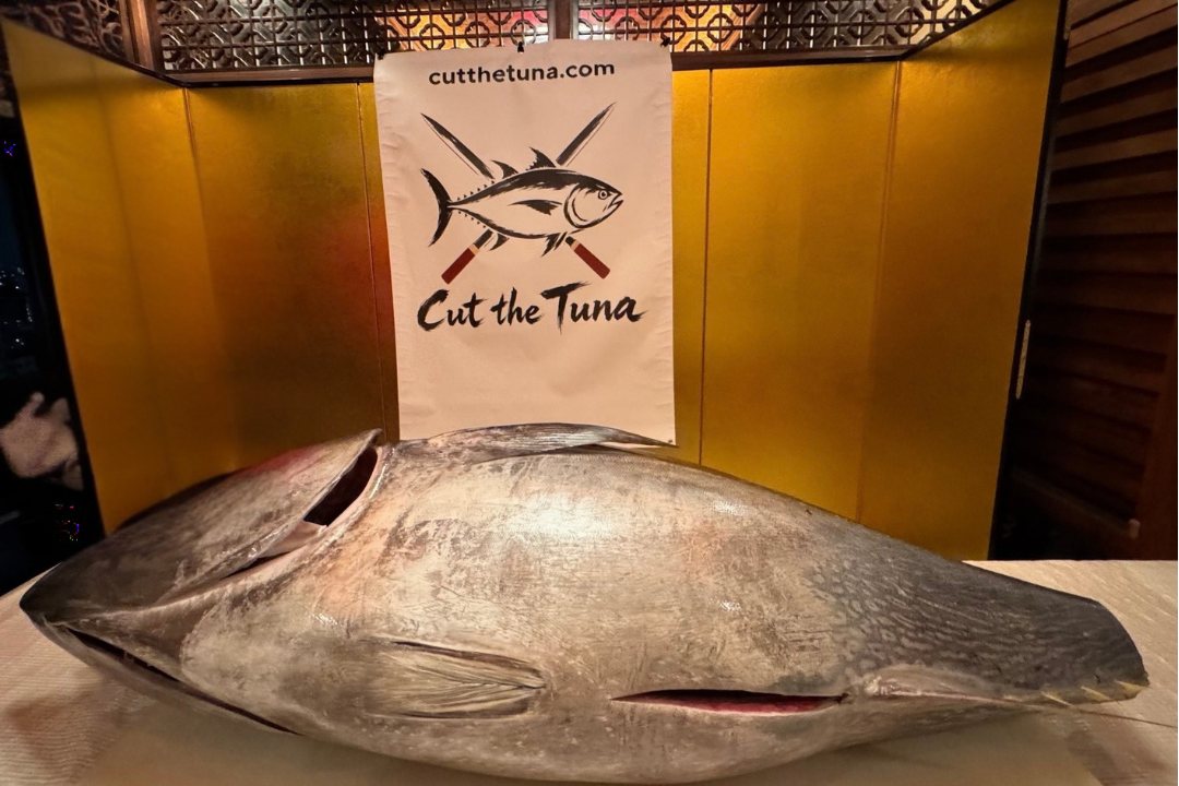 A whole tuna on the table before a private Cut the Tuna event in Tokyo, with the Cut the Tuna banner and a gold folding screen behind it